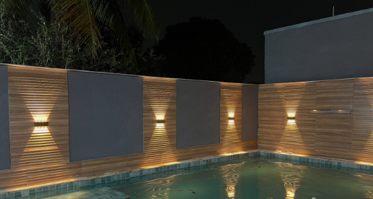 Luminárias de parede acesas ao redor de uma piscina à noite